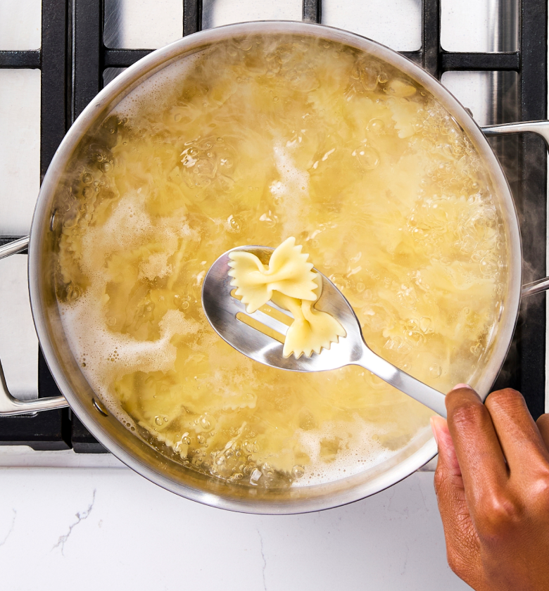 Bowtie farfalle pasta boiling in stainless steel pot on gas stove