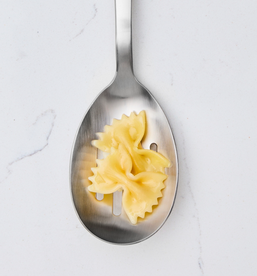Cooked farfalle bow-tie pasta on a stainless steel slotted spoon